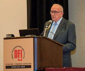 elderly man standing behind a podium