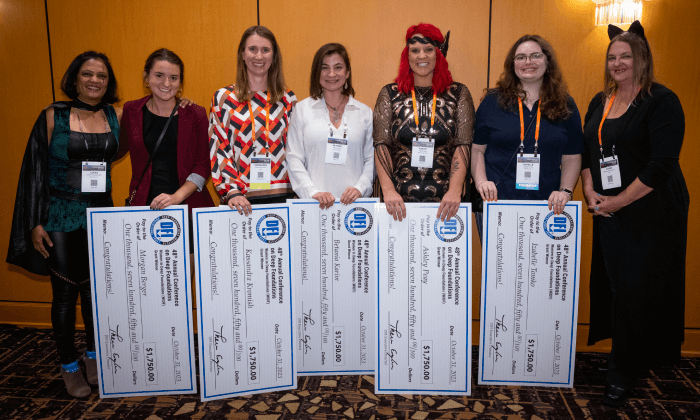 7 woman standing with 5 scholarship checks