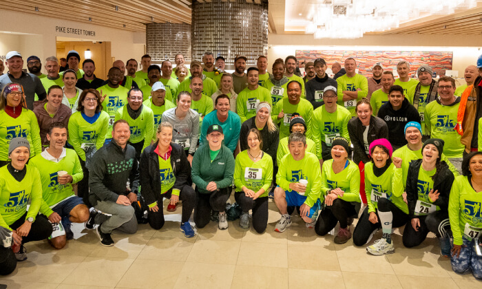 large group of men and women in running gear hi-vis clothing posing in a hotel lobby