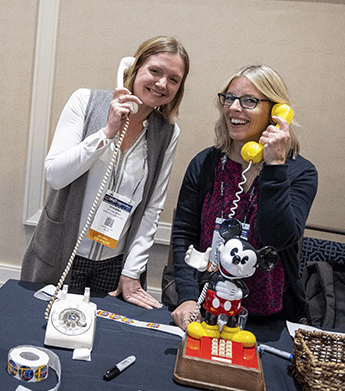 2 women holding corded phones to their ears