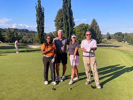 two men and two women posing with golf clubs on green grass