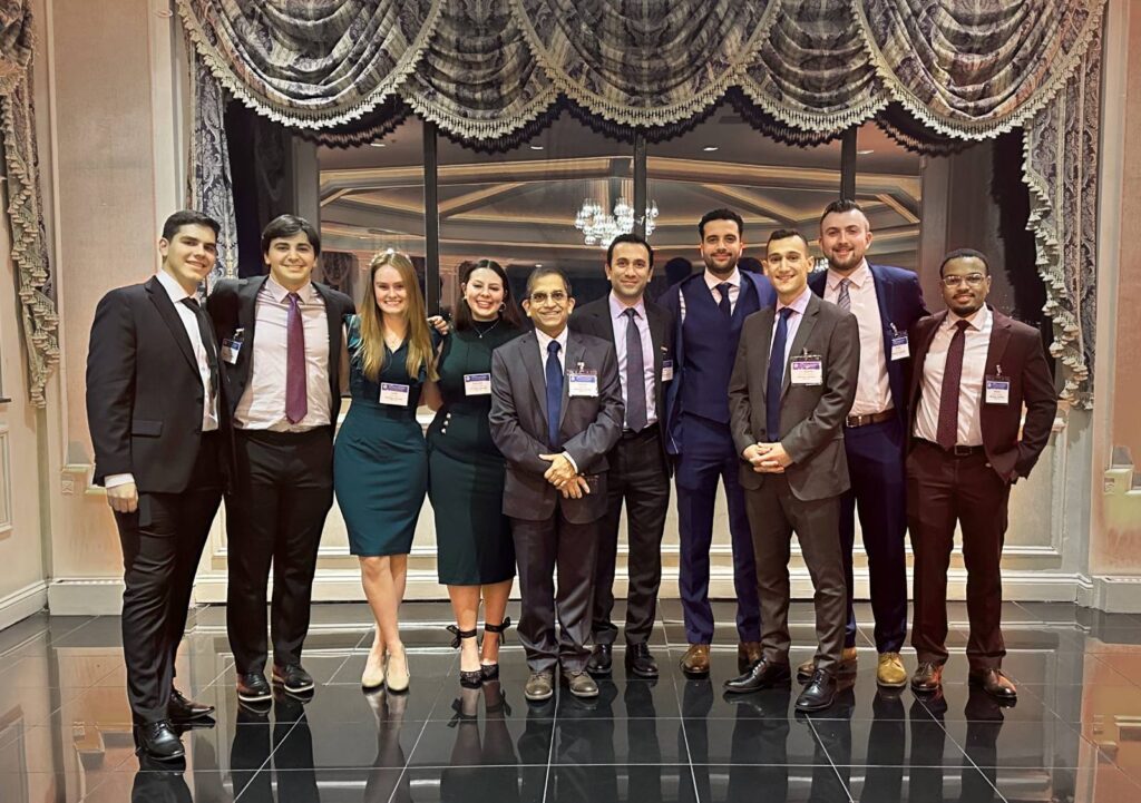 ten adults in formal dress posing in front of a large window